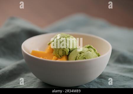 Grüner Matcha-Tee-Eis mit frischer Mango in weißer Schüssel, flacher Fokus Stockfoto