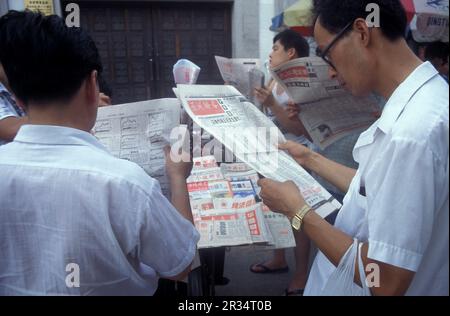 Menschen mit Börsenzeitungen in der Stadt Kunming in der Provinz Yunnan in China in ostasien. China, Yunnan, April 1996 Stockfoto