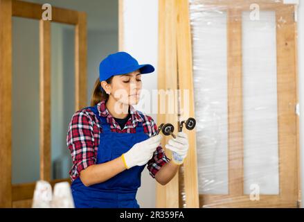 Woman builder assembling door handle Stockfoto