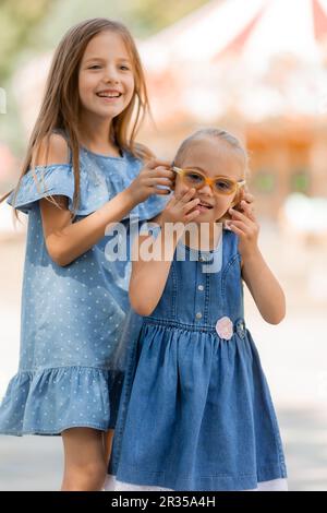 Zwei kleine Mädchen gehen im Sommer gerne im Vergnügungspark spazieren. Internationaler Kindertag. Ein Kind mit Down-Syndrom. Hochwertiges Foto Stockfoto