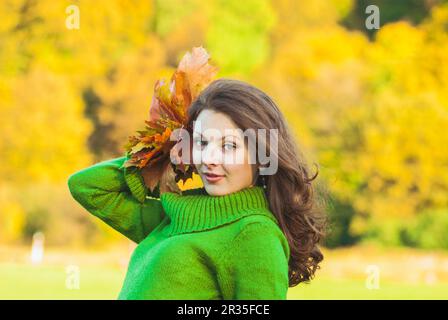 Schöne Frau mit herbstlichen Ahornblättern Stockfoto