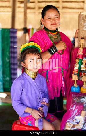 Eine Frau vom Langhals-Stamm, bekannt für die Metallringe um ihren Hals, die ihr Kind halten. Das Foto zeigt die Verbindung zwischen Mutter und Chi Stockfoto