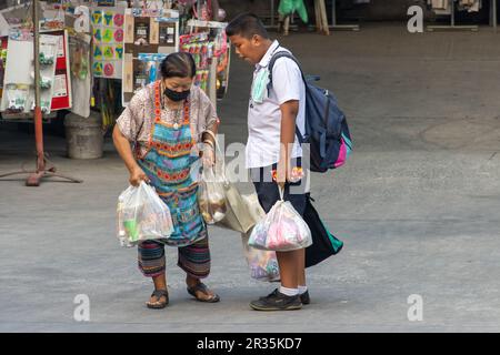 SAMUT PRAKAN, THAILAND, MÄRZ 03 2023, eine ältere Frau und ein Schuljunge gehen mit Einkaufstaschen auf die Straße Stockfoto