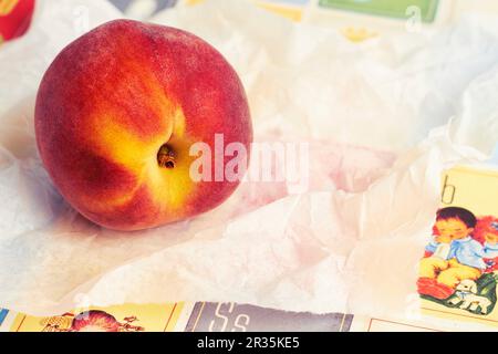 Ein frischer Pfirsich auf einem Stück weißem Papier Stockfoto