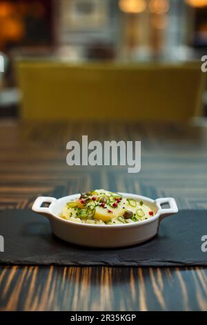 Kartoffelsalat mit Pfefferkörnern und Kapern in einer Schüssel auf einem Tisch in einem Restaurant Stockfoto