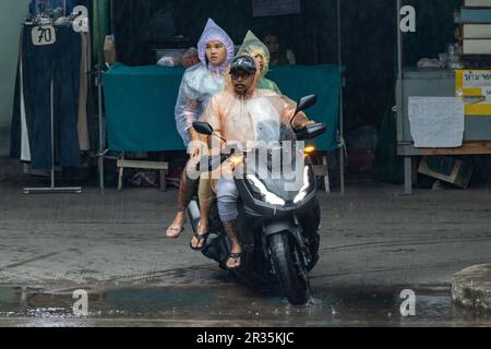 SAMUT PRAKAN, THAILAND, 10. Mai 2023, Eine Familie in Regenmänteln fährt ein Motorrad auf einer verregneten Straße Stockfoto