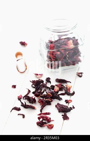 Getrocknete Hibiskusblüten in einem Glas und auf einem weißen Tuch Stockfoto