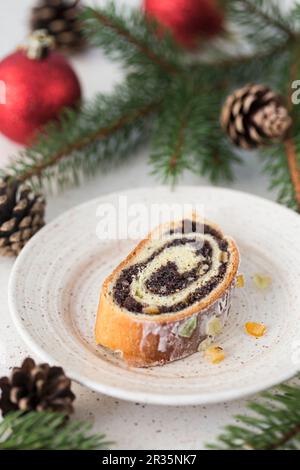 Ein Stück eines traditionellen polnischen Mohn-Brötchen-Kuchens mit Sahnehäubchen, getrockneten Früchten und Nüssen Stockfoto