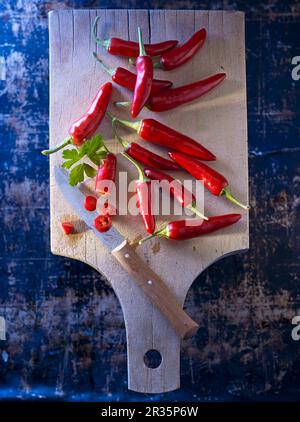 Rote Chili-Paprika auf einem Holzbrett mit flacher Petersilie Stockfoto
