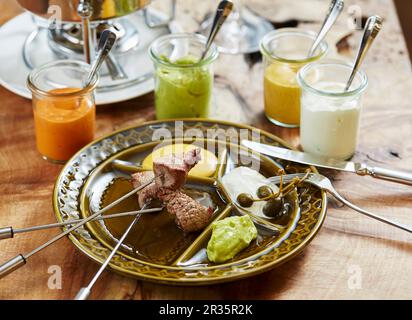 Fleischfondue und verschiedene Saucen Stockfoto