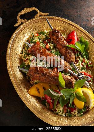 Orientalische, gehackte Lammspieße auf einem Bett Tabbouleh Stockfoto