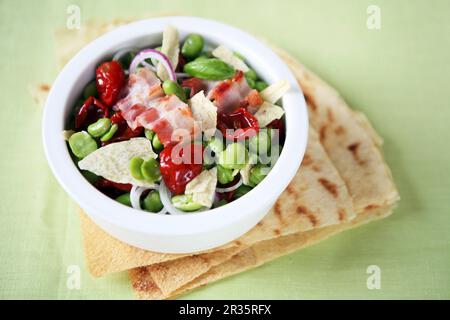 Dicke Bohnen mit Zwiebeln, getrocknete Tomaten, gegrillter Speck und ungesäuertes Brot Stockfoto