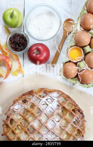 Apfelkuchen und Zutaten auf einem weißen Tisch Stockfoto