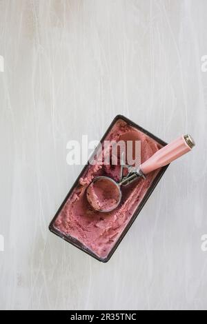 Hausgemachtes Erdbeereis in einem Behälter mit einem Eislöffel Stockfoto