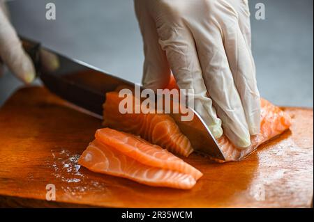 Fischfilet aus frischem rohen Lachs mit Küchenmesser zum Kochen von Speisen Meeresfrüchte Lachsfisch, Lachsfilet auf Holzschneidbrett Stockfoto