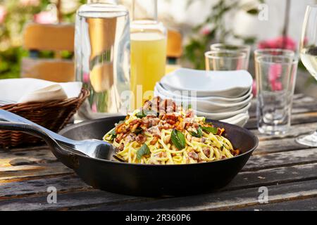 Spaghetti mit Pfifferlingpilzen in einer Pfanne auf einem Gartentisch Stockfoto