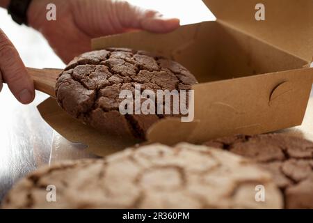 Ein Mann, der Schokoladenkekse in eine Schachtel packt Stockfoto