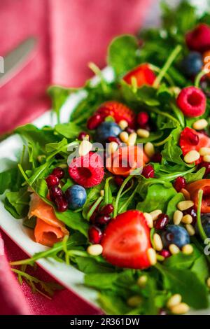 Gesunder Salat mit Rucola, Spinat, geräuchertem Lachs und Beeren Stockfoto