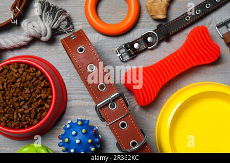 Flach liegend mit Hundehalsband, Spielzeug und Futter auf grauem Holztisch Stockfoto