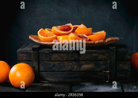 Keile sizilianischer Blutorangen auf einem Teller und in einer Holzkiste Stockfoto