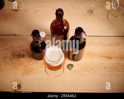 Ein Glas Bier und drei geöffnete Bierflaschen Stockfoto