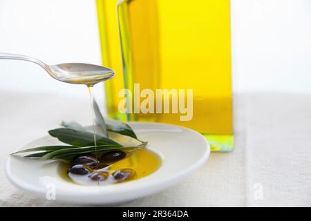 Olivenöl wird über Leben in einer Schüssel gegossen Stockfoto