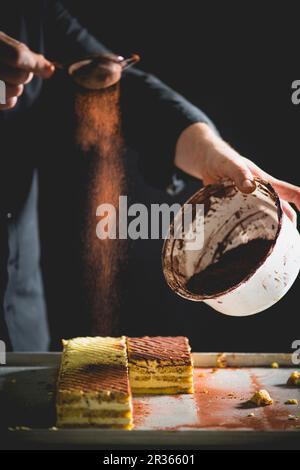 Tiramisu-Scheiben werden mit Kakao abgewischt Stockfoto