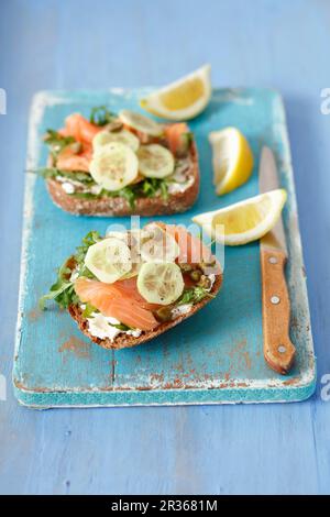 Vollkornrollen mit geräuchertem Lachs, Frischkäse, Gurke und Kapern Stockfoto