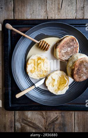 Englische Muffins mit Honig auf einem Teller (von oben gesehen) Stockfoto