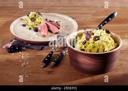 Kartoffeldip mit schwarzen Oliven und Knoblauch mit Rindersteak Stockfoto