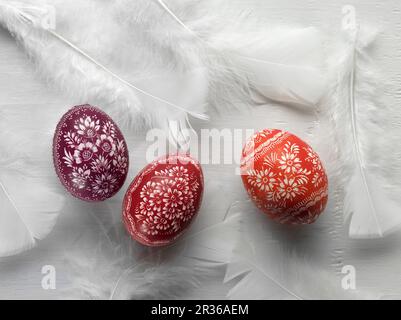 Sorbische Ostereier und weiße Federn auf einer weißen Oberfläche Stockfoto