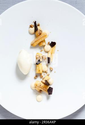 Marinierte Bananen mit geriebener Schokolade, VollkornMüsli, Bananencreme und Vanilleeis Stockfoto