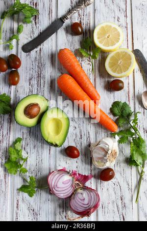 Eine Anordnung mit Avocado, Karotten, Zitronen, Zwiebeln und Tomaten Stockfoto