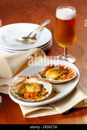 Überbackene Jakobsmuscheln und Bier Stockfoto