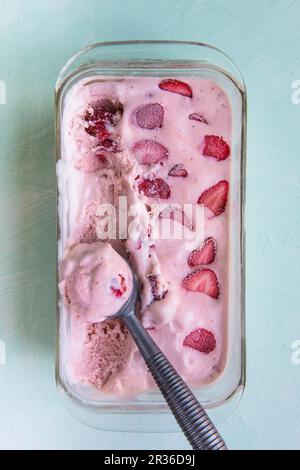 Hausgemachtes Erdbeereis mit einem Eislöffel in einem Glasgericht (von oben gesehen) Stockfoto