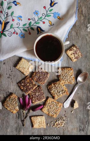 Kekse mit Leinsamen, Sonnenblumenkernen und Sesamsamen, serviert mit einer Tasse Kaffee Stockfoto