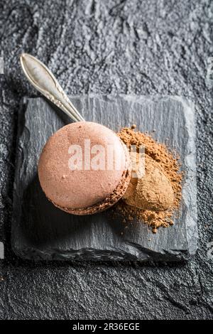 Schokoladenmakronen mit Kakaopulver auf schwarzem Stein Stockfoto