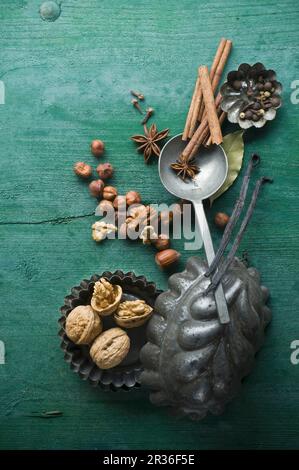 Verschiedene weihnachtliche Gewürze und Nüsse in Backformen auf einem rustikalen Holzmöbeln Oberfläche Stockfoto