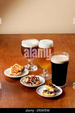 Verschiedene Gläser Bier mit würzigen Tartlets Stockfoto