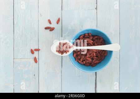 Getrocknete Goji Beeren auf einem Löffel und in einer Schüssel auf eine rustikale Oberfläche Stockfoto