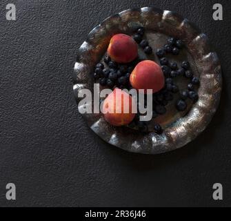 Frische Heidelbeeren und Pfirsiche auf einer Metallplatte (siehe oben) Stockfoto