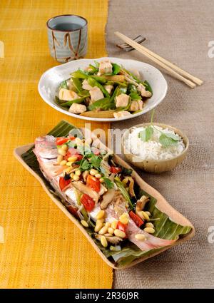 Gedünstete pandora in Bananenblättern und gebratenes Hähnchen mit Gemüse Stockfoto
