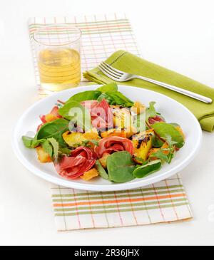 Salat mit gegrillten Pfirsichen, Rote-Beete-Blättern, Schinken und Croutons Stockfoto