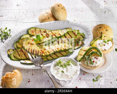 Marinierte gegrillte Zucchini mit Schafskäse Sauce und Brötchen Stockfoto