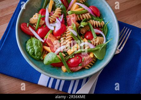 Nudelsalat mit Tomaten, Spinat und Speck Stockfoto