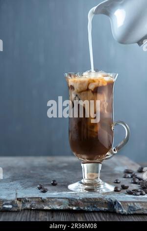 Milch wird dem Kaffee hinzugefügt Stockfoto