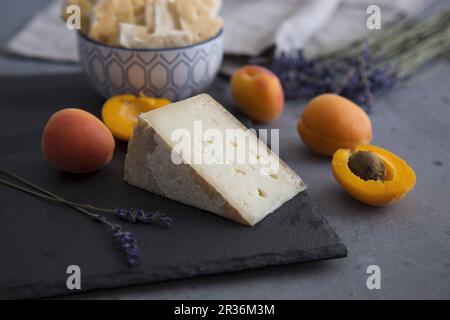 Aprikosen und Ziegenkäse auf einer Schiefertafel platter mit Crackern und Lavendelblüten Stockfoto