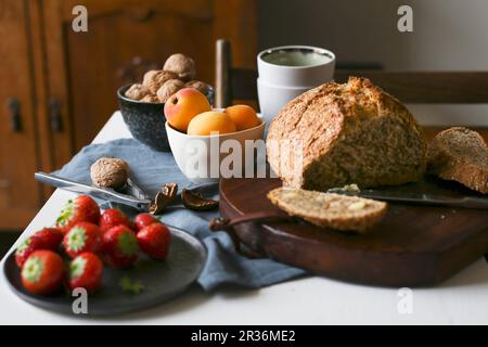 Ein Frühstückstisch mit Brot, Aprikosen, Erdbeeren und Walnüssen Stockfoto