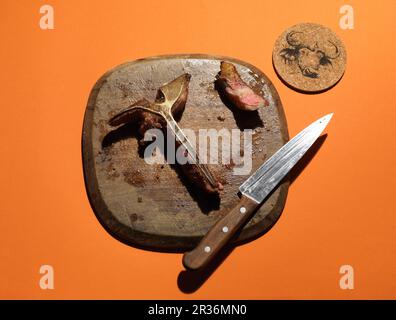 Die Reste eines T-Bone Steak auf einem Holzbrett Stockfoto