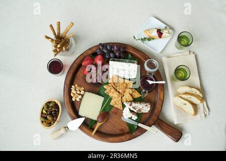 Ein Cheesebaord mit frischem Obst, Soßen, Nüssen, Kapern, Brotstangen, Cracker und Weißbrot Stockfoto